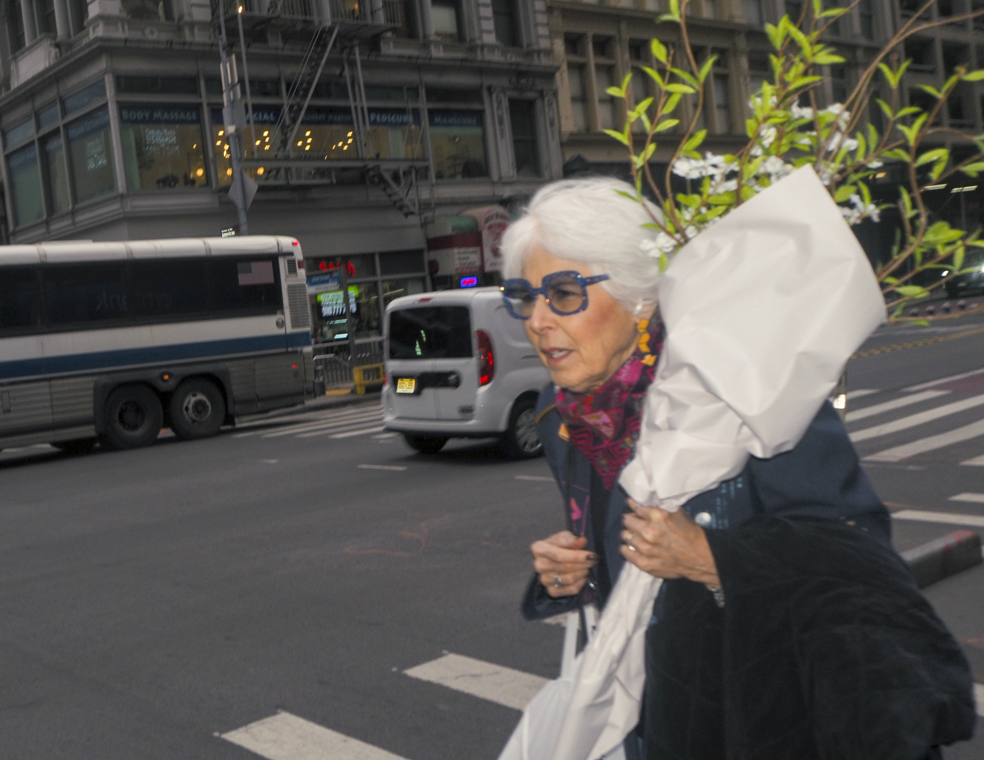 Two elderly women walking on NYC street with white flowers