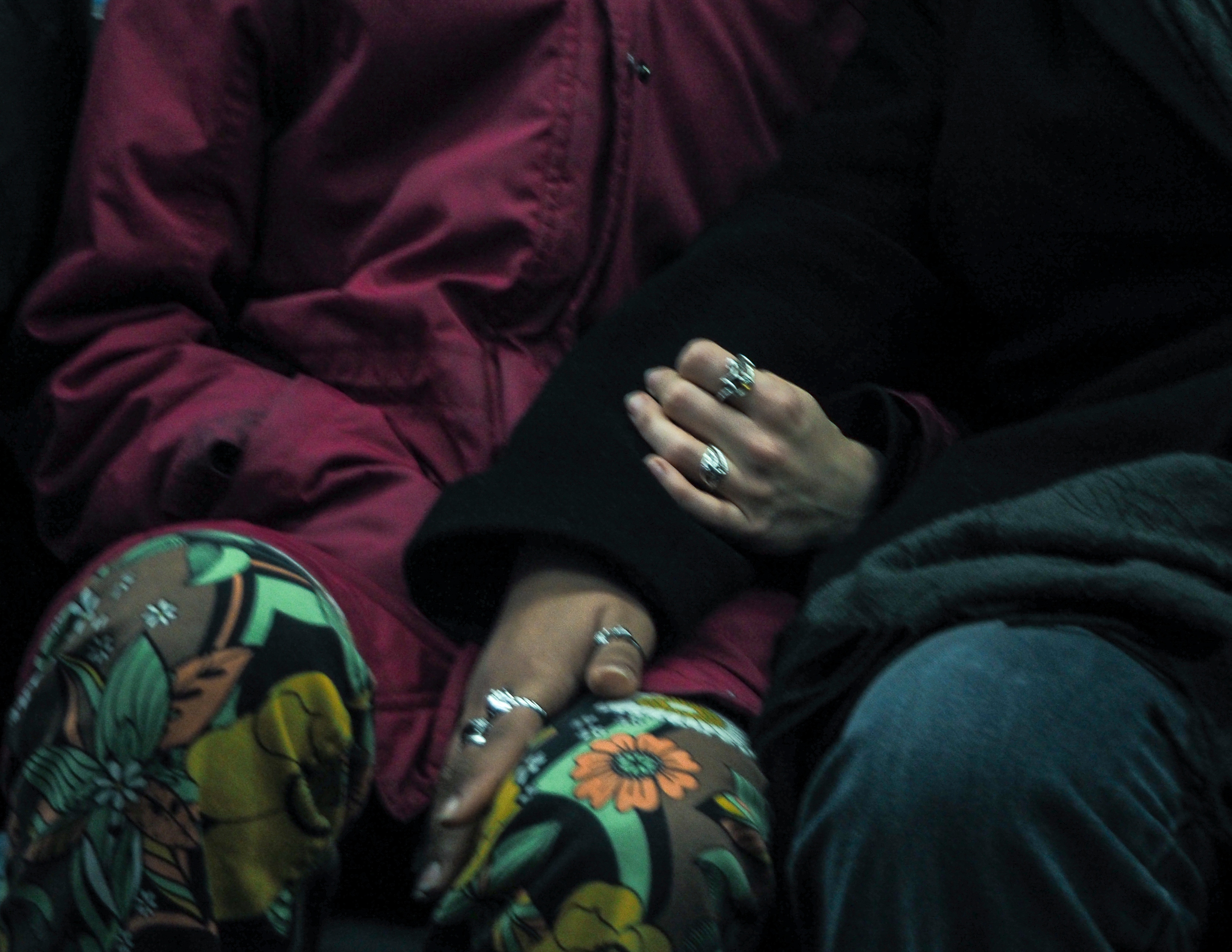 Close-up of hands with silver rings and colorful floral pattern clothing