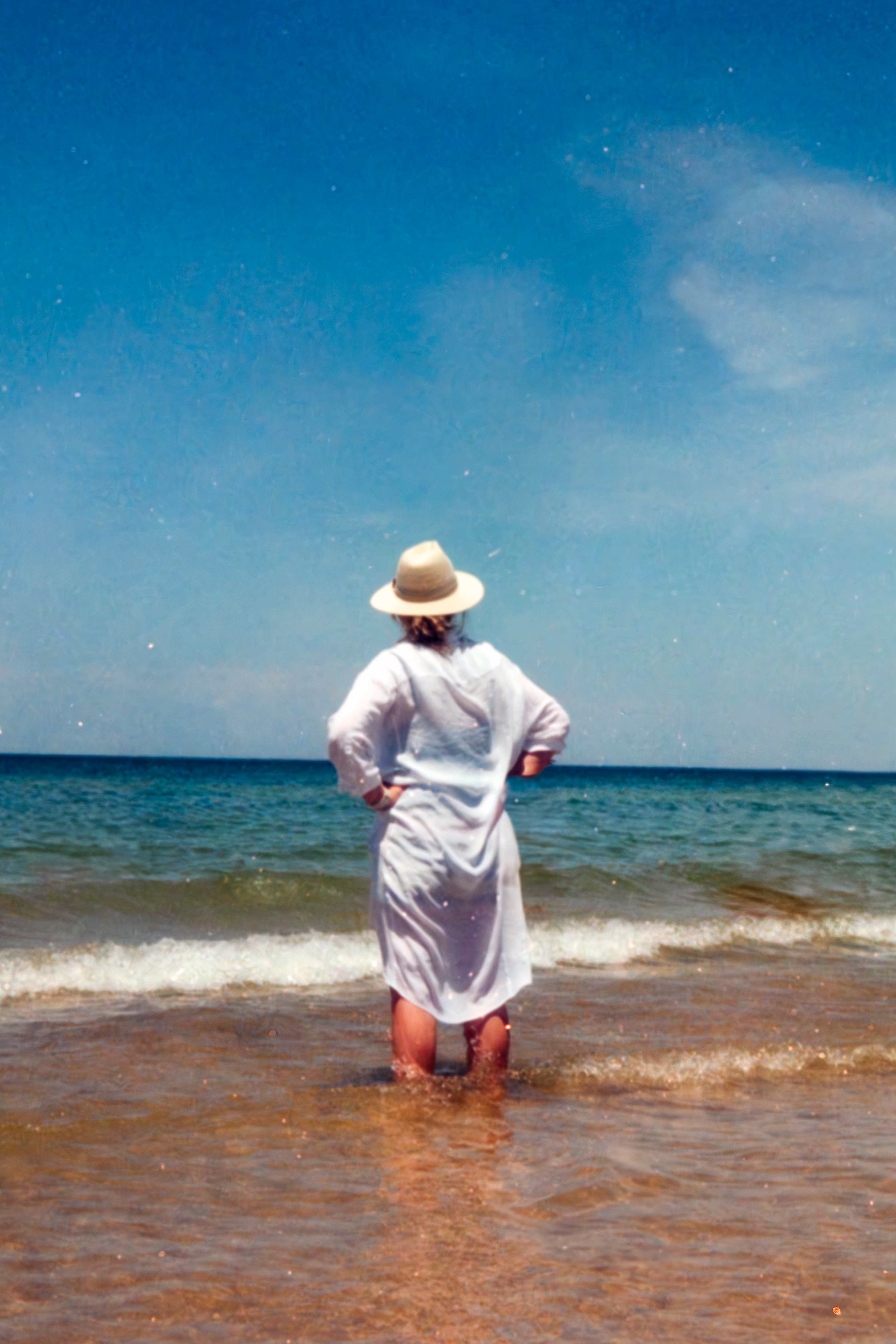 Woman in white dress standing in ocean waves