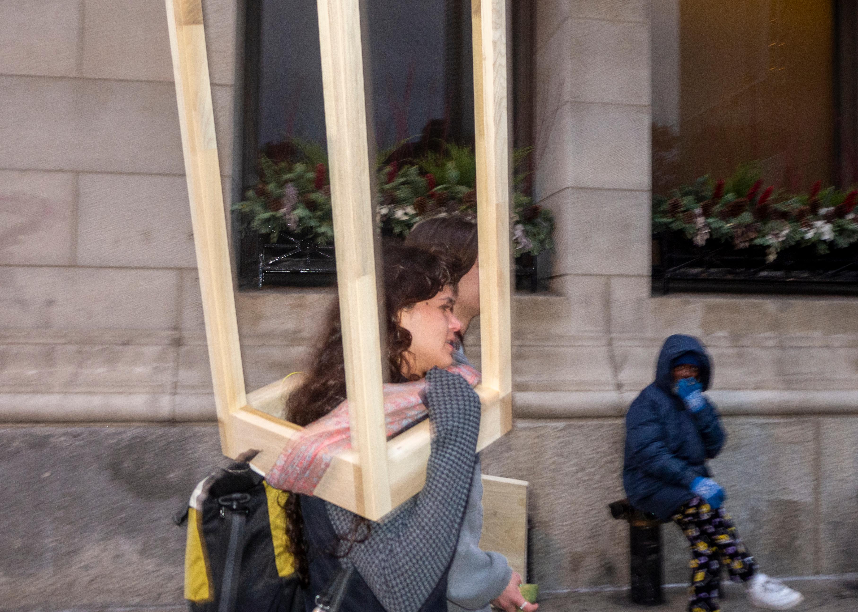 Woman carrying wooden stool frame, motion blur on Chicago street