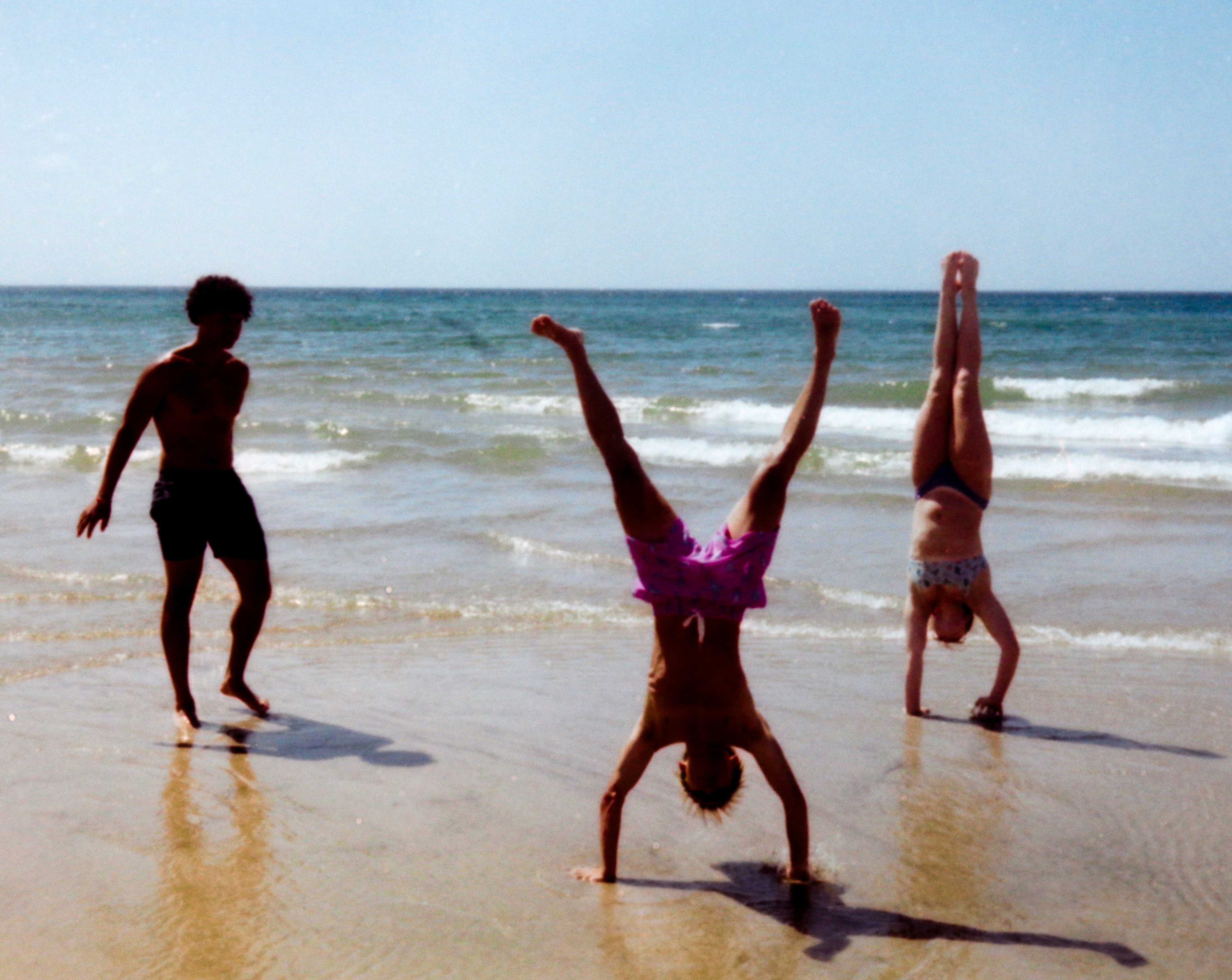 People doing handstands on beach